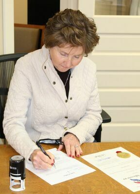 Public Administrator, Paula Evans, signs the required paperwork at her swearing-in.